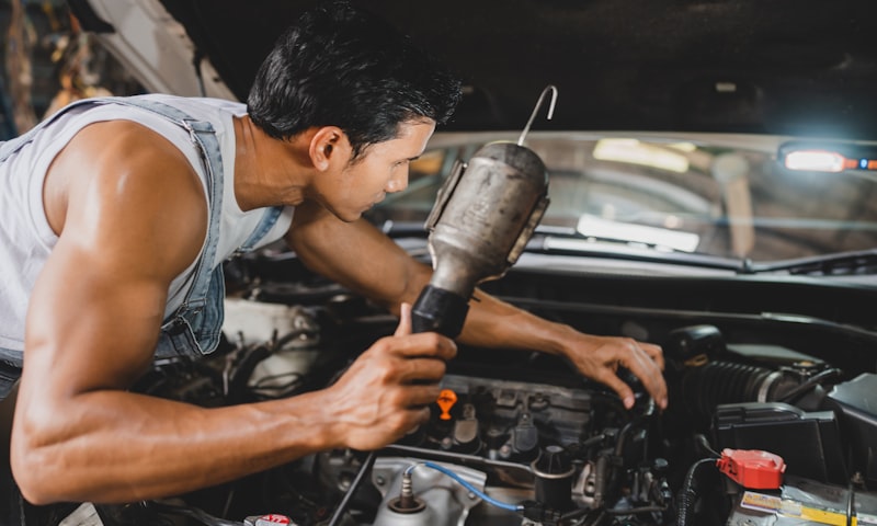 Mechanic inspecting car engine during vehicle maintenance service